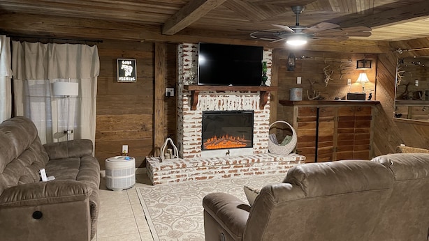Ein gemütliches Wohnzimmer mit Kamin, Ledersofas und Deckenventilator.