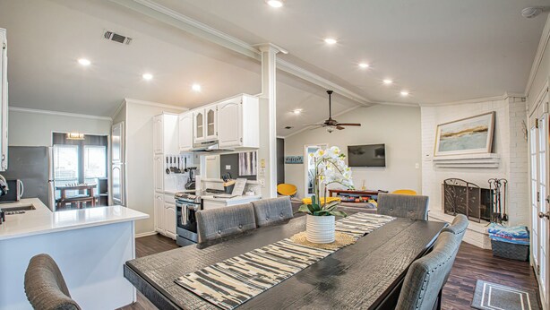 Una cocina moderna con armarios blancos, una isla central y una zona de comedor con una mesa larga y sillas.
