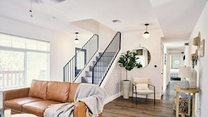 A modern living room with a leather sofa, a round coffee table, and a staircase with black railings. - Hill Country Farmhouse Near Canyon Lake + Wineries (Fischer)