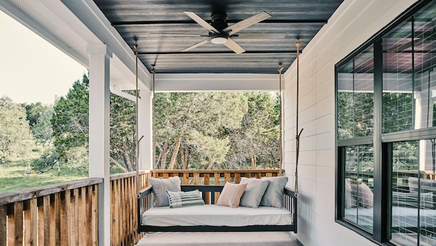 A covered porch with a wooden deck, a ceiling fan, and a view of the surrounding trees. - Hill Country Farmhouse Near Canyon Lake + Wineries (Fischer)