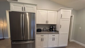 Una cocina con armarios blancos, un refrigerador de acero inoxidable, una cafetera y un tostador.