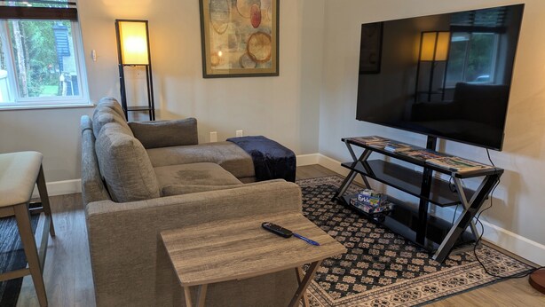 Una sala de estar con un sofá modular, un televisor sobre un mueble bajo, una mesita y una alfombra estampada.