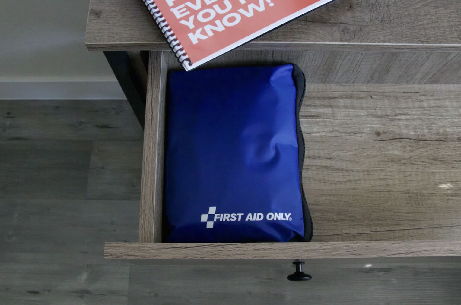 A drawer containing a blue pillow with a "First Aid Only" label.