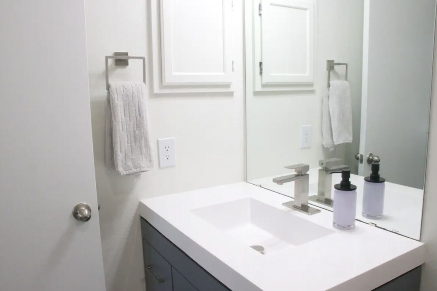 A modern bathroom with a white sink, a mirror, and a towel hanging on a rack.