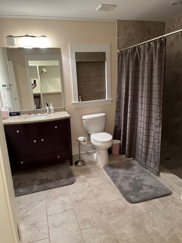 A bathroom with a toilet, sink, vanity, and a shower area.