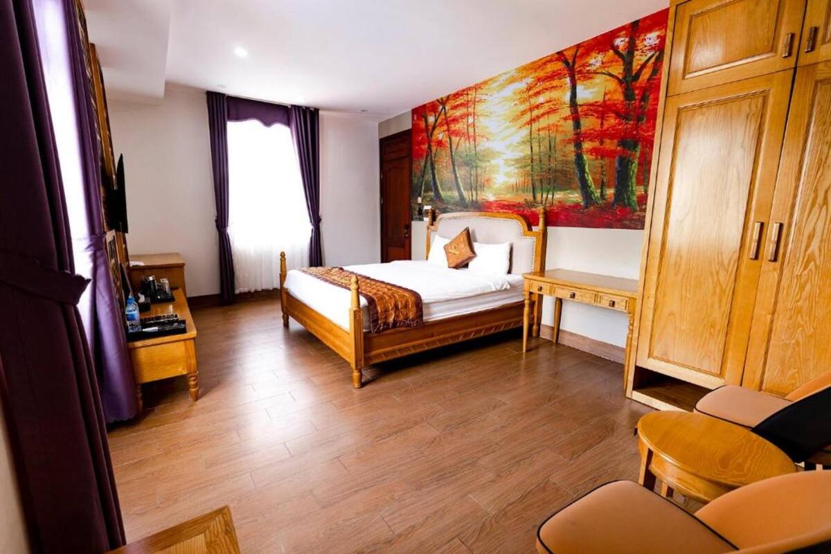 Une chambre d’hôtel avec un lit en bois, une table de chevet, un bureau et une armoire.