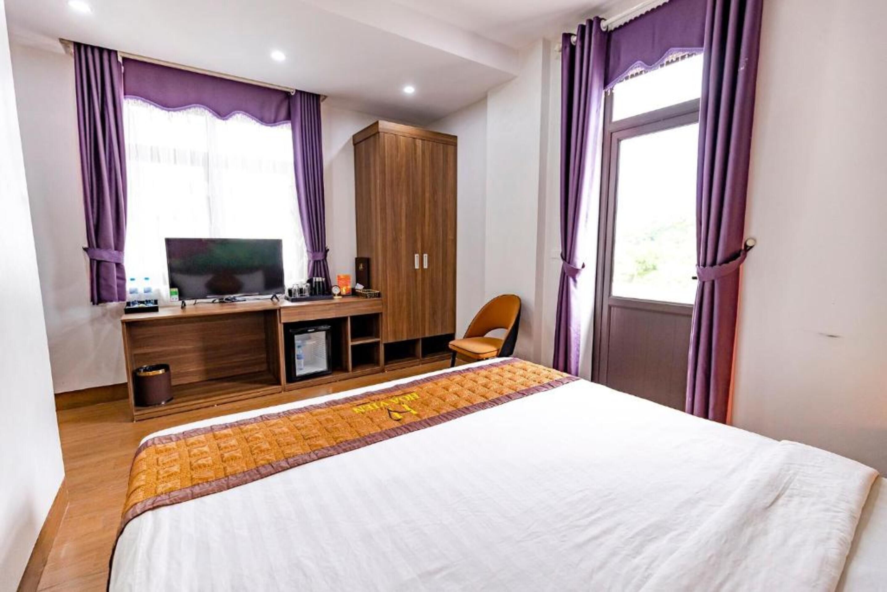 Una habitació d'hotel amb un llit, un escriptori amb un ordinador, una televisió i un armari.
