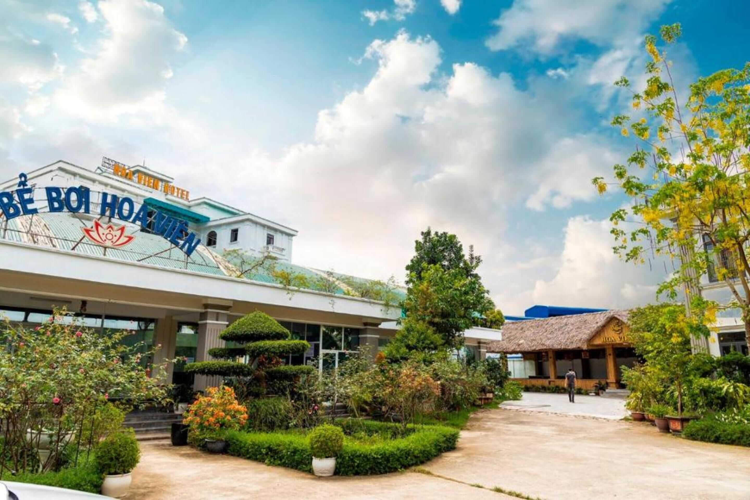 Un hotel con un cartel grande que dice "BE BOI HOANHEN" y un jardín bien cuidado al frente.