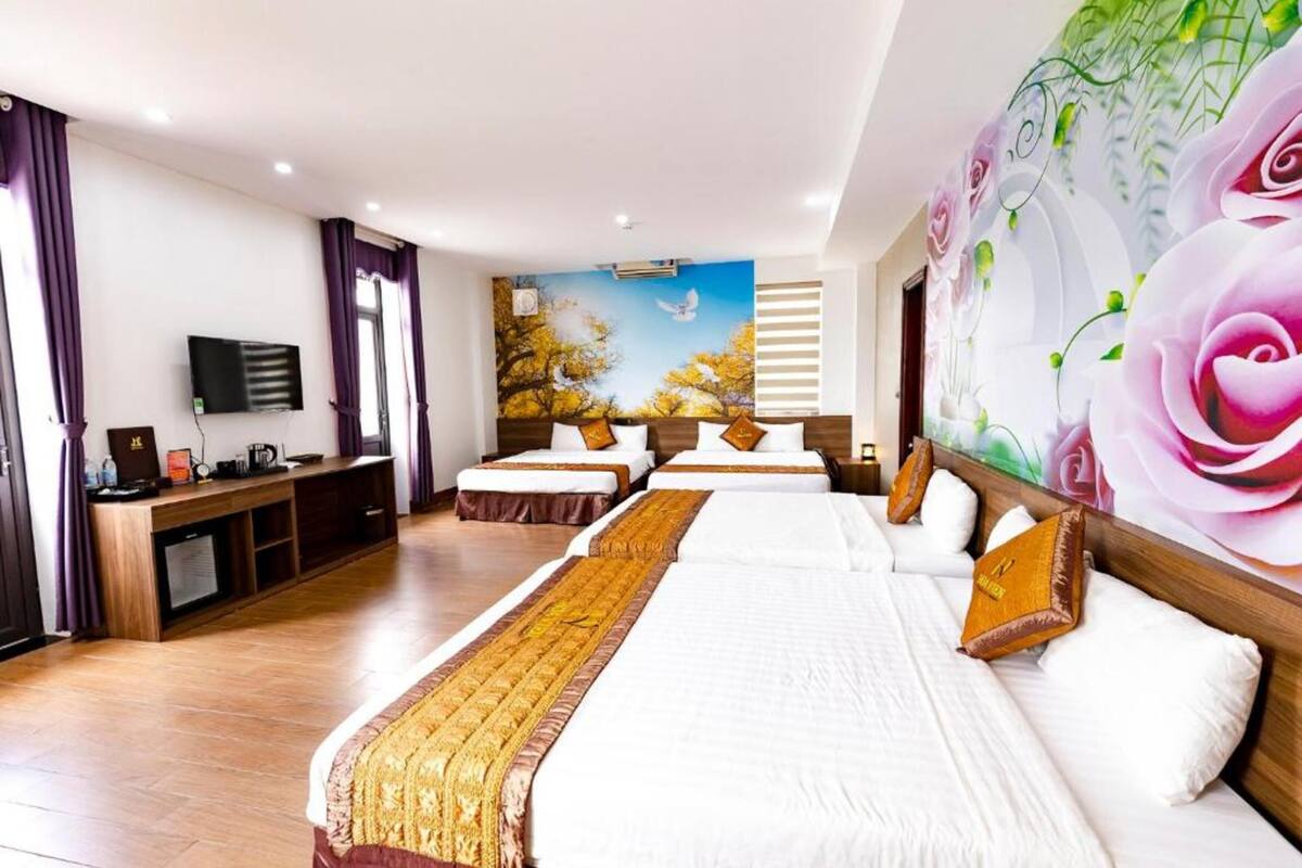 Une chambre d’hôtel avec un grand lit, une télévision, un bureau et une fresque murale.