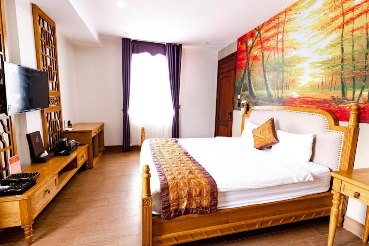 Une chambre à coucher avec un lit, une télévision, un bureau et un tableau accroché au mur.