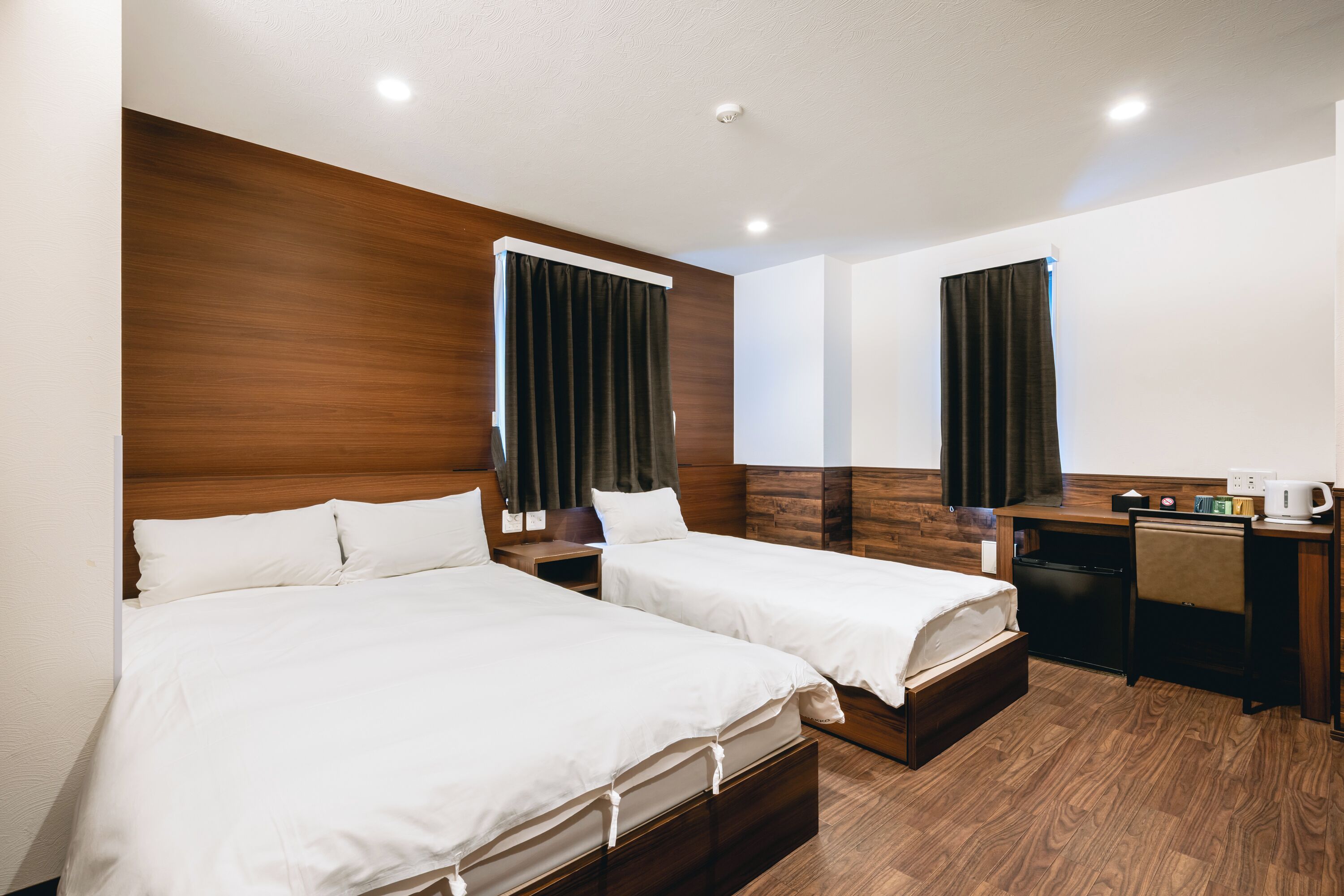 Een hotelkamer met twee bedden, een bureau en een koffieapparaat.