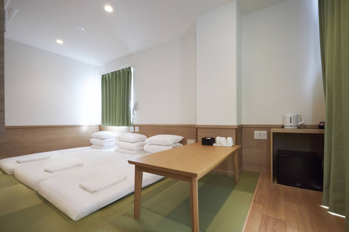 A hotel room with a bed, a wooden table, a television, and a coffee maker.