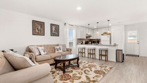 A modern living room with a beige sofa, a glass coffee table, and a patterned rug.