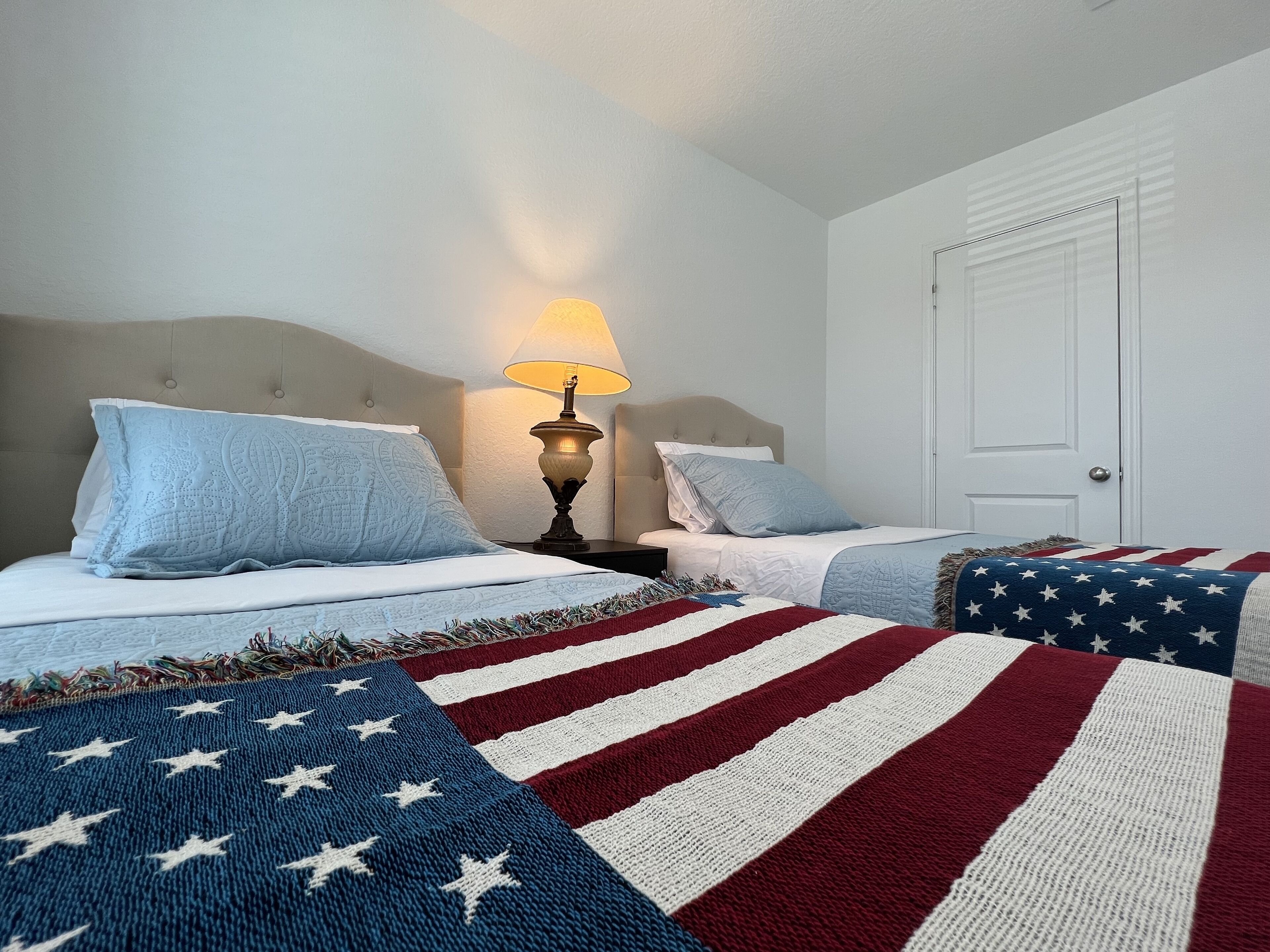 Une chambre d’hôtel avec deux lits, une lampe et une porte.