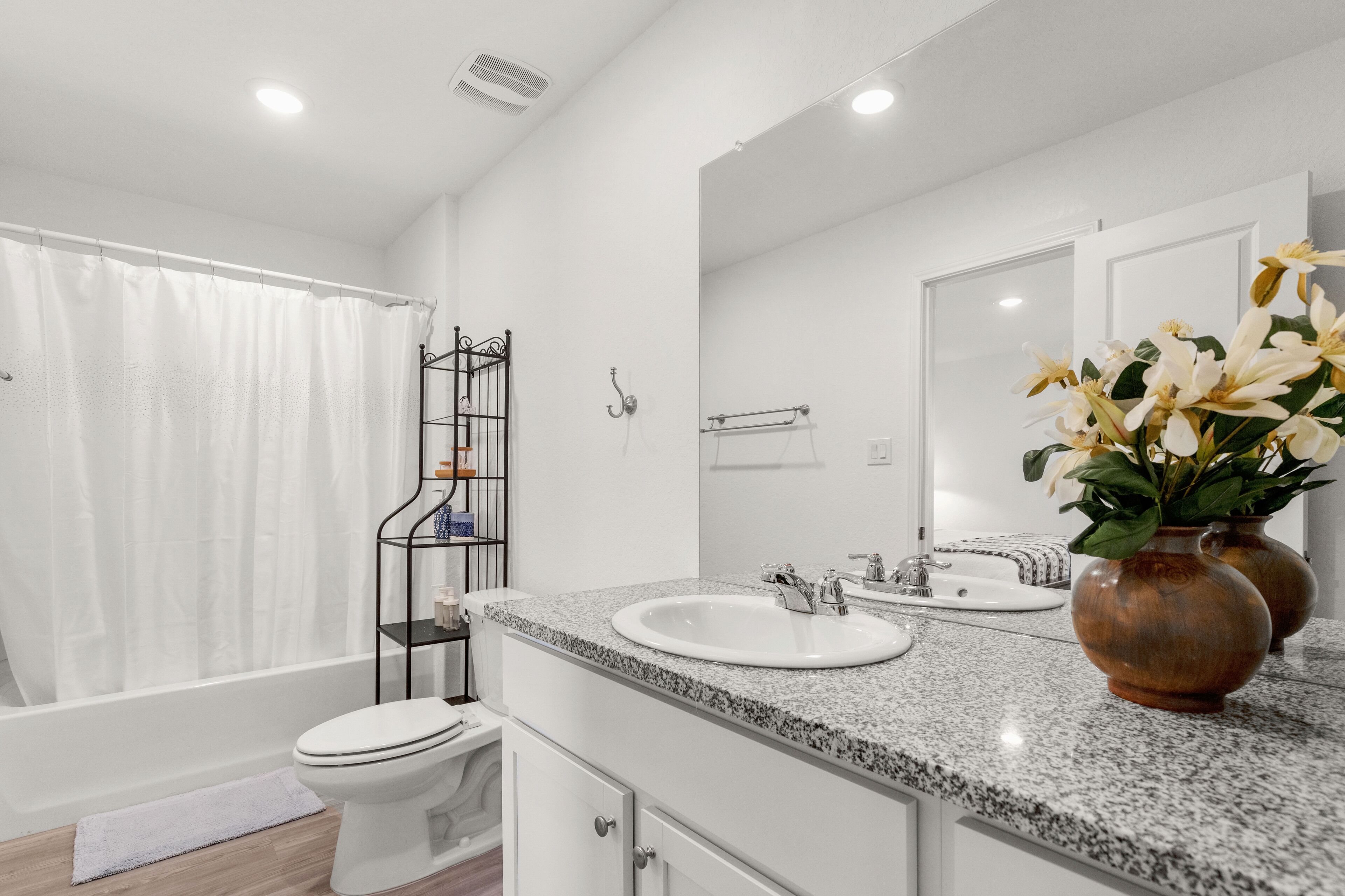 Un baño moderno con inodoro blanco, lavamanos con espejo y zona de ducha.