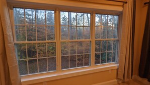 Ein Zimmer mit großem Fenster mit Blick auf ein bewaldetes Gebiet.