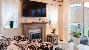 Una sala de estar con chimenea, un televisor montado encima y un sofá estampado.