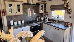Une cuisine moderne avec des meubles blancs, une hotte de cuisinière en acier inoxydable et une décoration représentant une girafe suspendue.