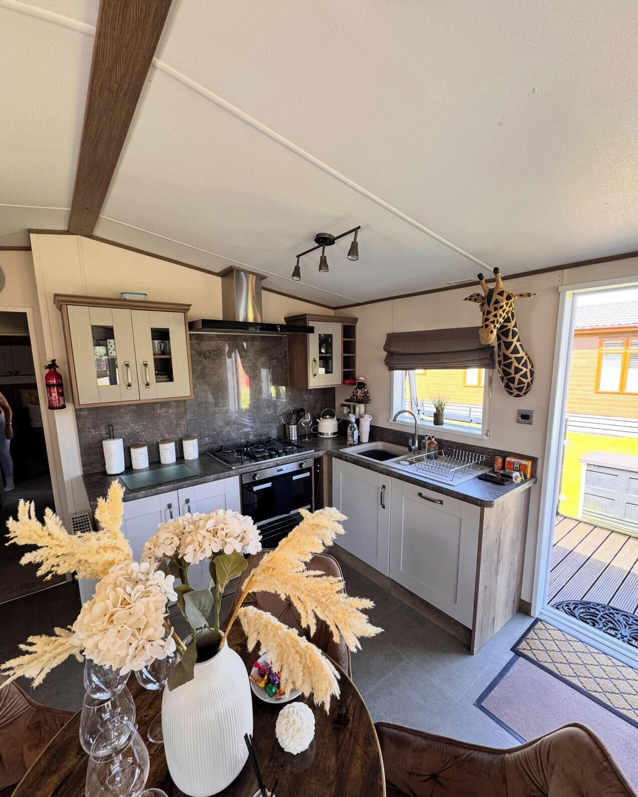 Une cuisine moderne dotée d’un îlot central, de meubles de rangement intégrés et d’une décoration représentant une girafe suspendue.
