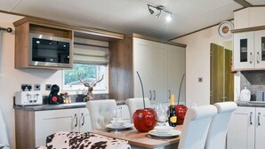 Una cocina compacta con electrodomésticos modernos, un comedor con sofá estampado con motivos de vaca y una pequeña mesa de comedor para dos.
