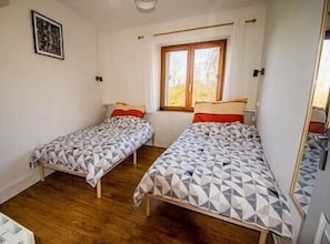 A room with two single beds, a window with curtains, and a wooden floor. - House - Sleeps 6 - Parking - Garden (Gorron)