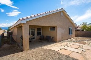 A single-story house with a patio area featuring a stone floor and two chairs. - Casa Chiliwood - Short Walk to Petroglyphs / Taylor Ranch (Albuquerque)