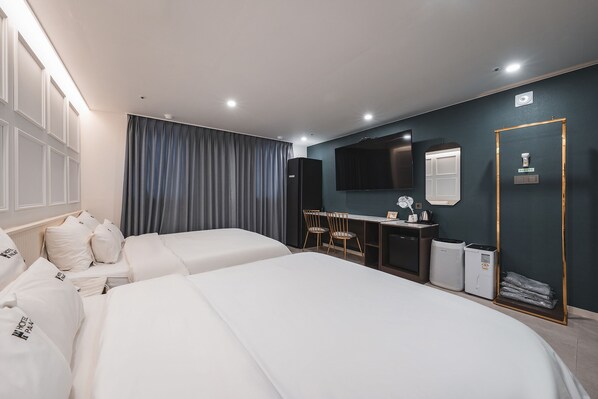 A hotel room with two beds, a desk, a chair, a TV, and a mirror.