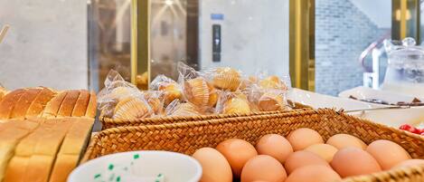 Un bufé de desayuno con pan, bollería, huevos y una pequeña fuente de salsas.
