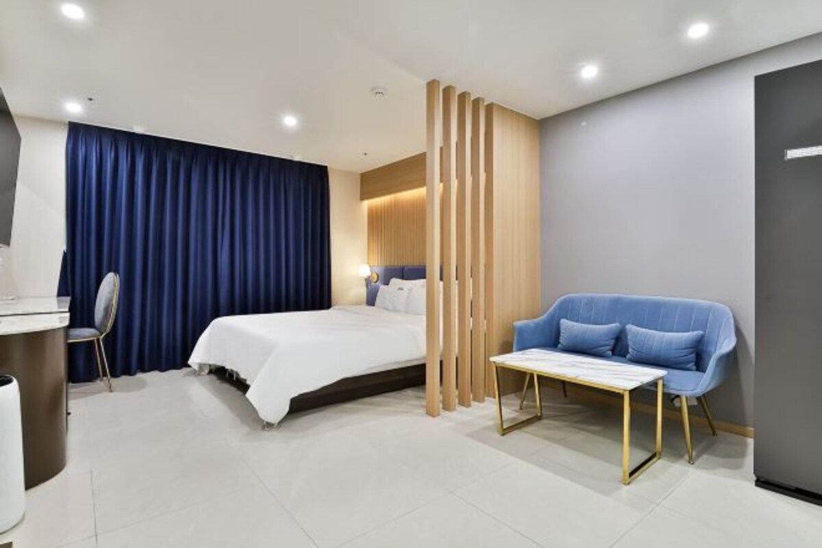 Una habitación de hotel moderna con cama, escritorio, silla y sofá.