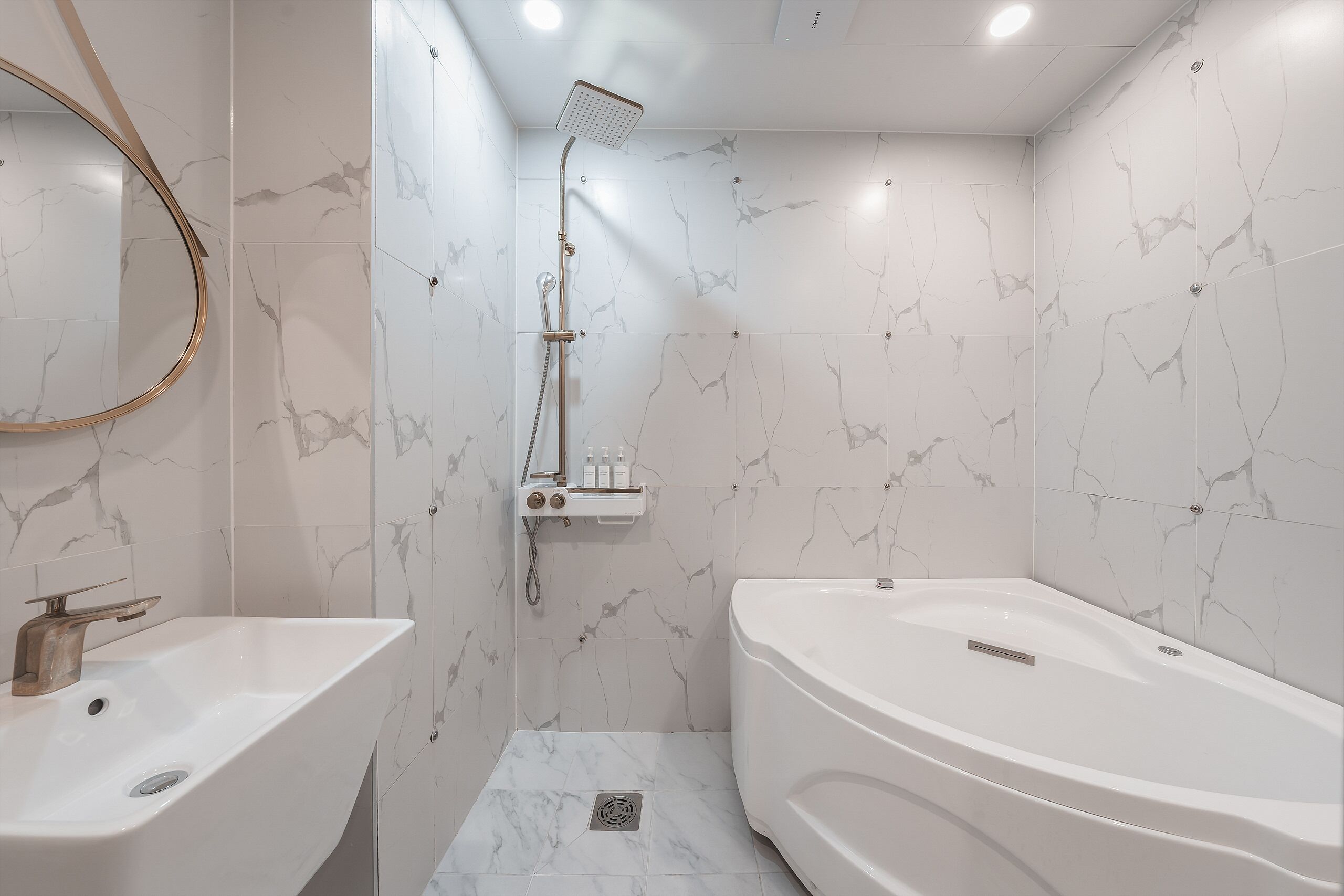 Une salle de bain moderne avec une baignoire sur pieds, un lavabo et une douche équipée d’un pommeau de douche amovible.