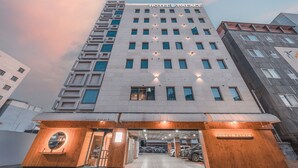 A multi-story hotel with a modern design, featuring a prominent entrance with a wooden facade and illuminated signage. - Hotel Palace Gyeongju (Gyeongju)