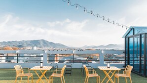 An outdoor seating area with tables and chairs, a string of lights, and a view of distant mountains. - Hotel Palace Gyeongju (Gyeongju)