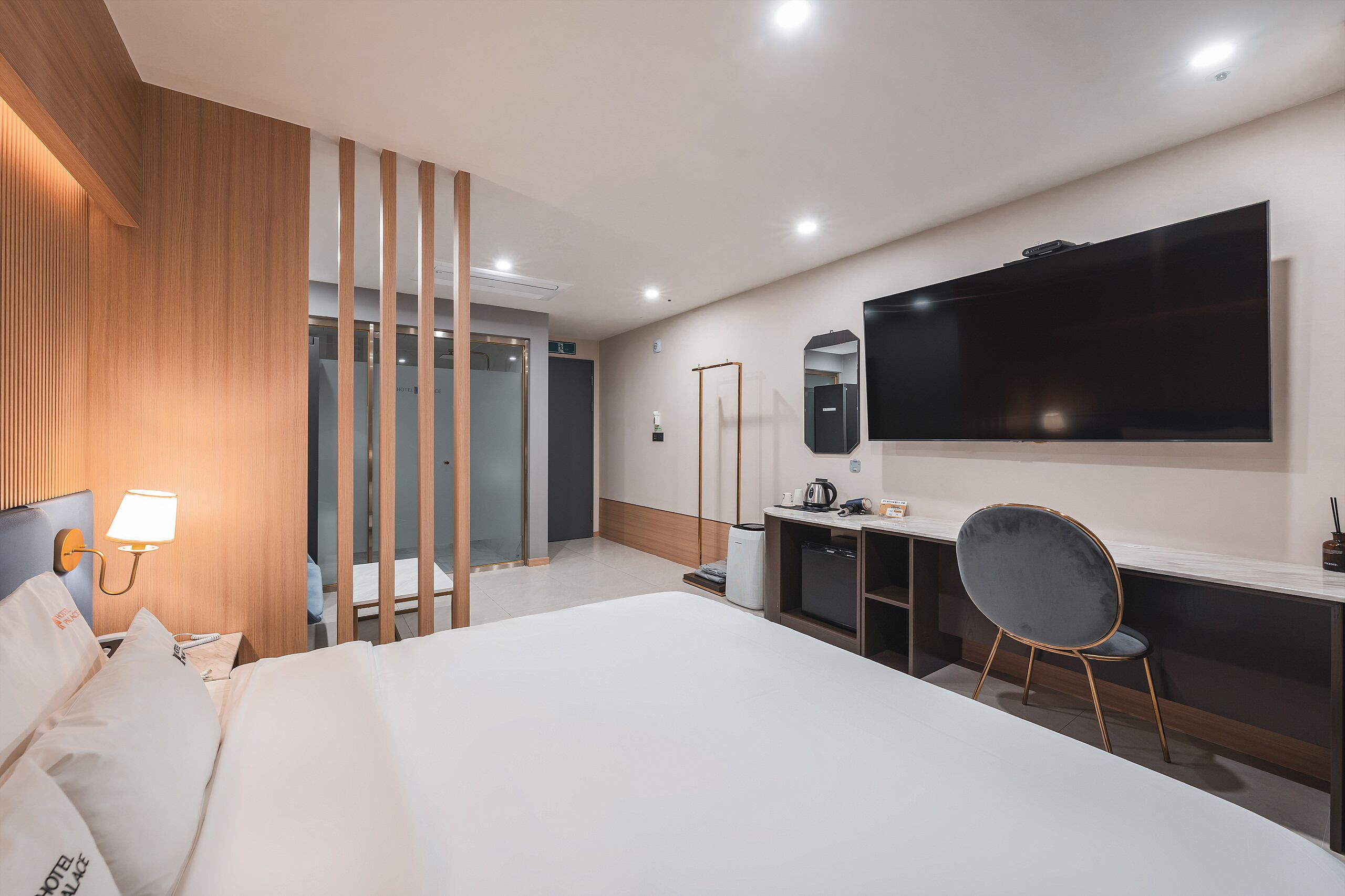Une chambre d’hôtel moderne équipée d’un grand lit, d’un bureau, d’une chaise, d’une télévision et d’un miroir.