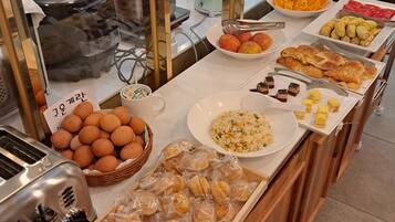 A buffet with various food items including bread, pastries, and fruits.