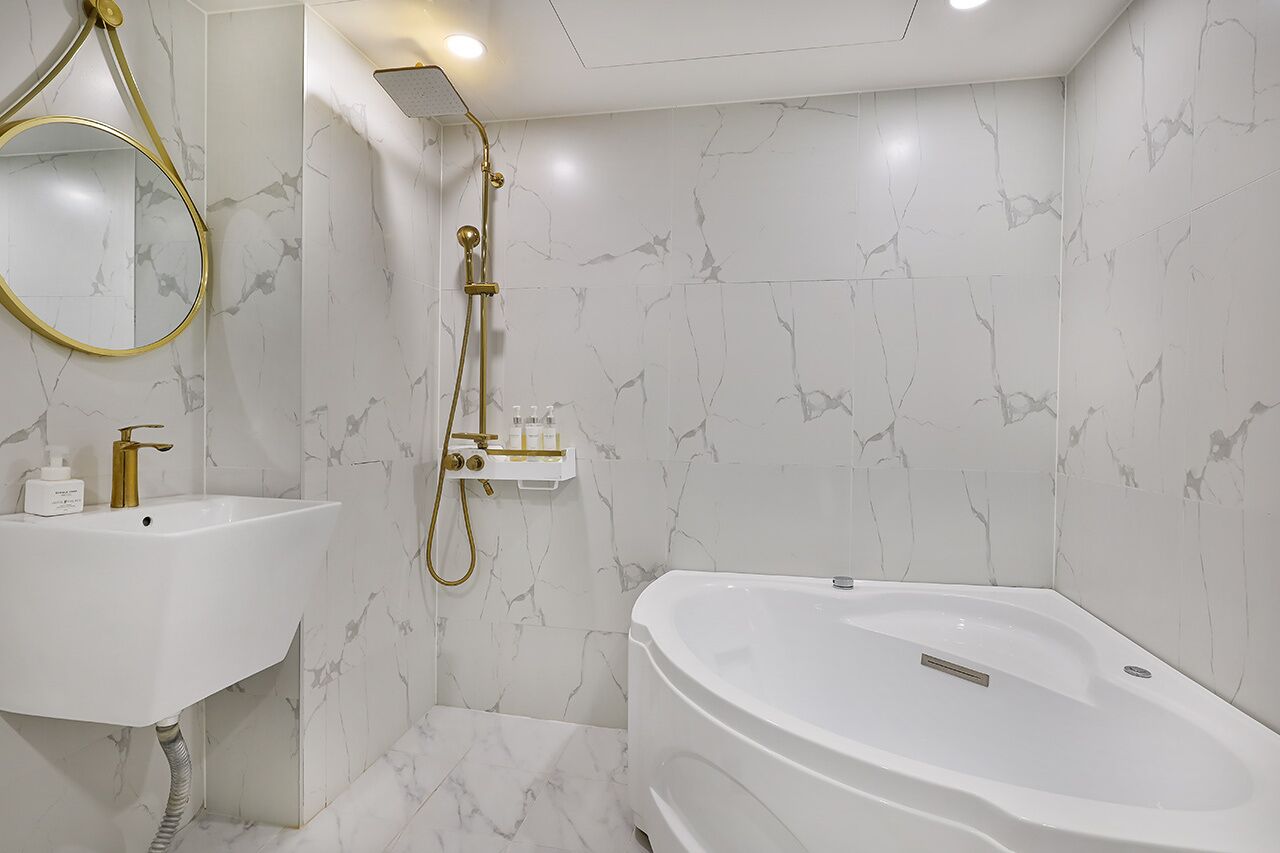 A modern bathroom with a freestanding bathtub, a pedestal sink, and a wall-mounted shower.