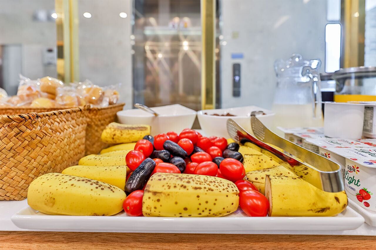 A breakfast buffet with bananas, tomatoes, and olives.