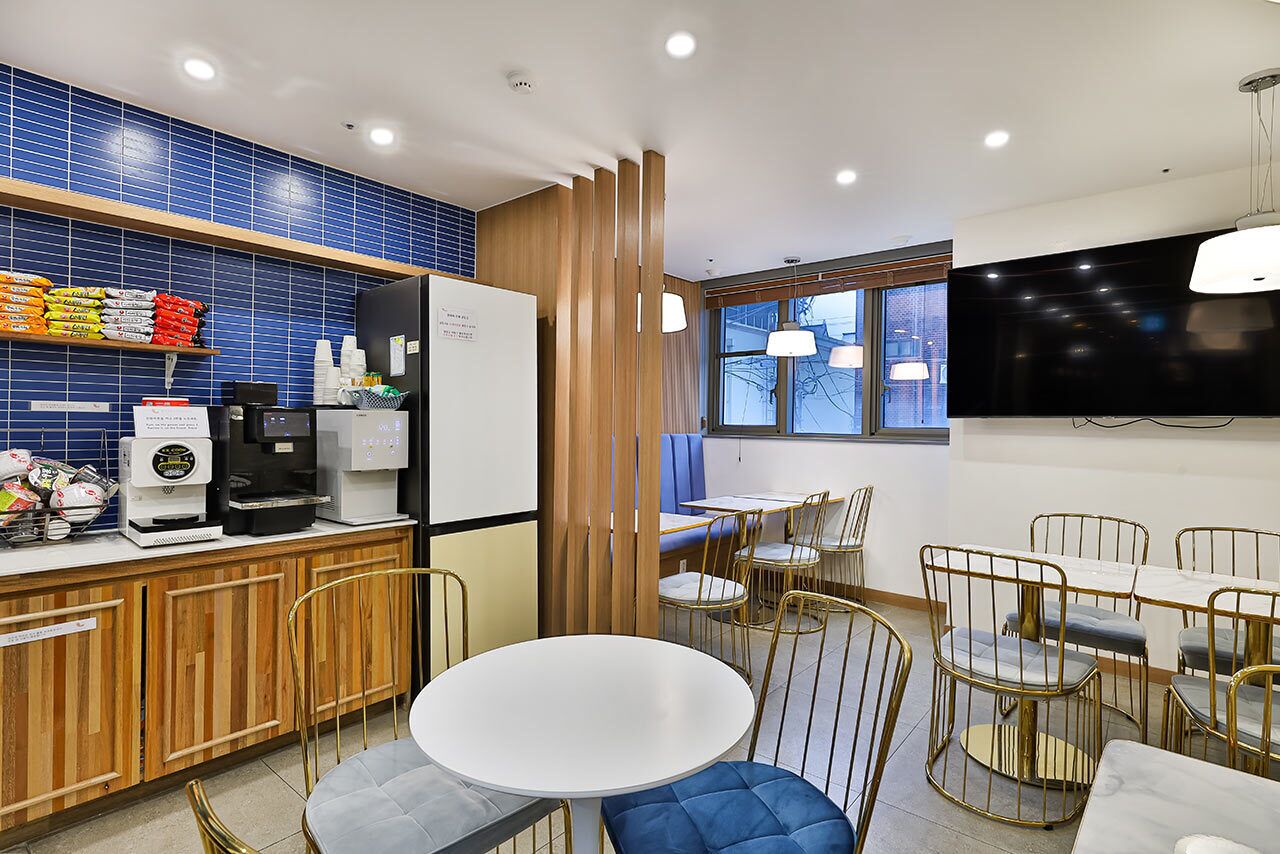 Un área de cocina moderna con cafetera, refrigerador y salpicadero de azulejos azules.