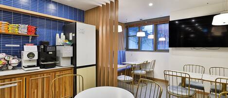 Un área de cocina moderna con cafetera, refrigerador y salpicadero de azulejos azules.