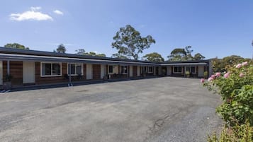 Een motel met een binnentuin, houten gevel en een grindpad.
