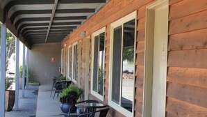 A covered outdoor area with wooden walls, potted plants, and tables and chairs. - Chalambar Motel (Ararat)