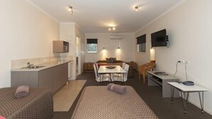 A compact hotel room with a kitchenette, a dining area, and a TV. - Chalambar Motel (Ararat)