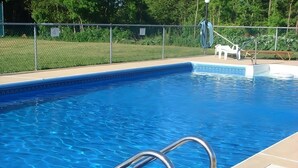 Una piscina con una escalera de metal y un área cercada.