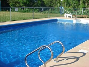 En swimmingpool med en metalstige og et hegn.