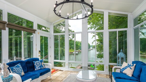 A sunroom with large windows, wicker furniture, and a chandelier. - Shoreside Oasis - Amazing Views & Spacious 5BR 4BA (Mooresville)