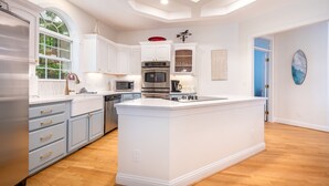 A spacious kitchen with white cabinetry, a central island, and a large window providing natural light. - Shoreside Oasis - Amazing Views & Spacious 5BR 4BA (Mooresville)