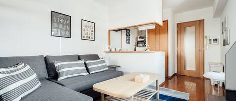 A modern living room with a grey sofa, a wooden coffee table, and a striped rug.