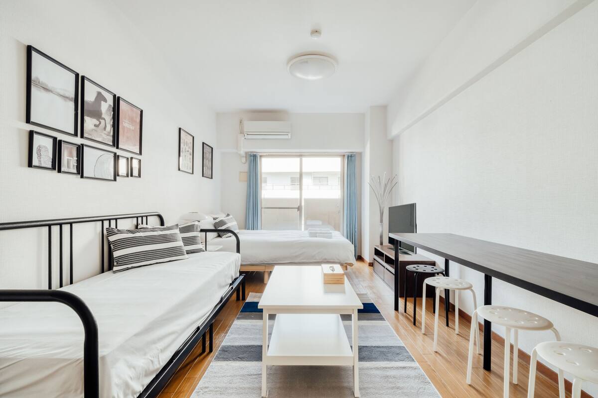 Quarto de hotel moderno com cama, uma mesa pequena, televisão e janela com cortinas.