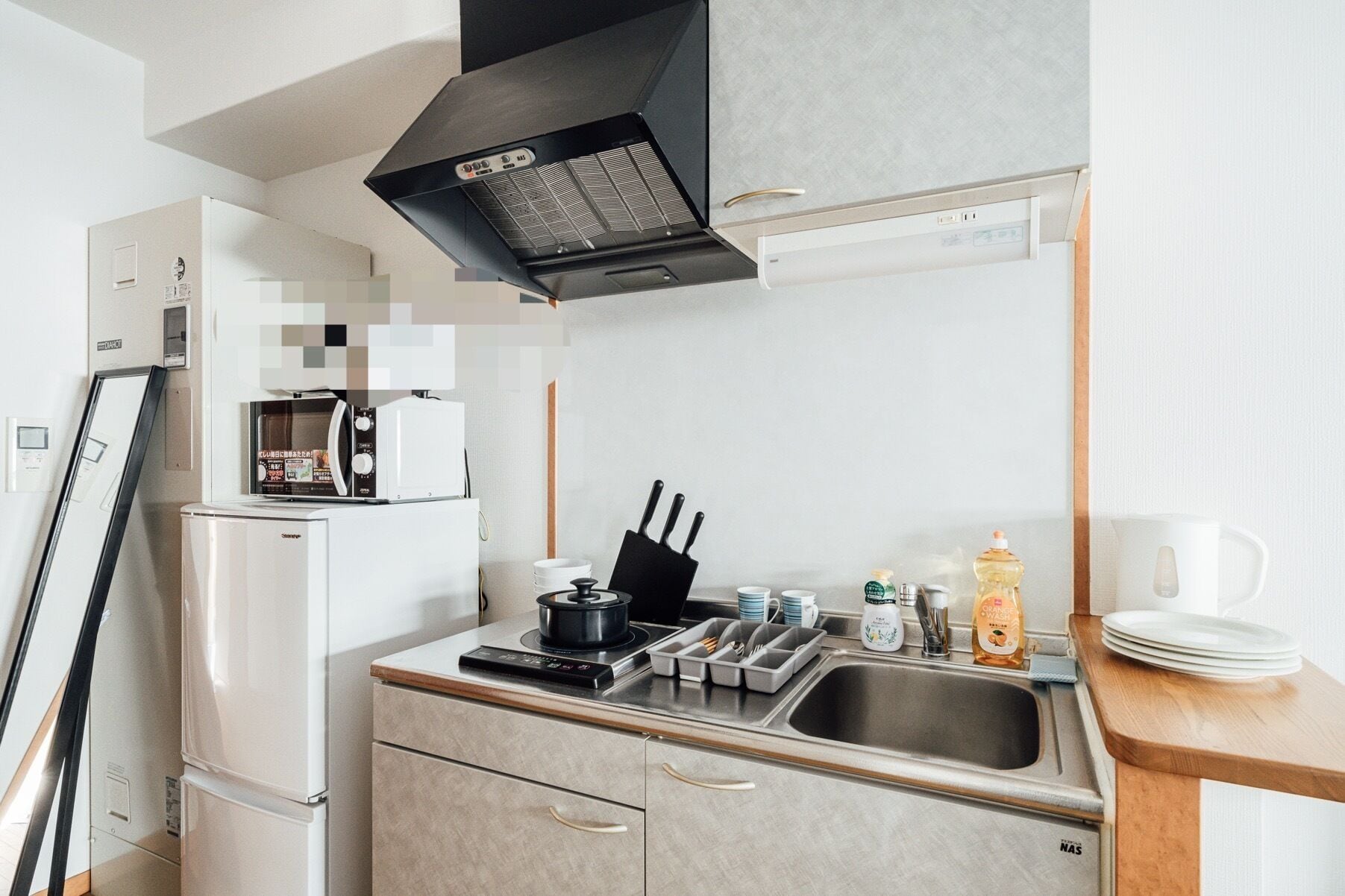 Una cocina compacta equipada con refrigerador, microondas, estufa, pileta y cafetera.