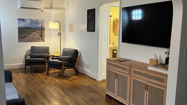 Un salon équipé d’un téléviseur à écran plat, d’un ventilateur de plafond, d’une cheminée et d’un coin repas avec un buffet en bois.