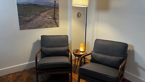 Deux fauteuils, un lampadaire et un tableau représentant un paysage accroché au mur.